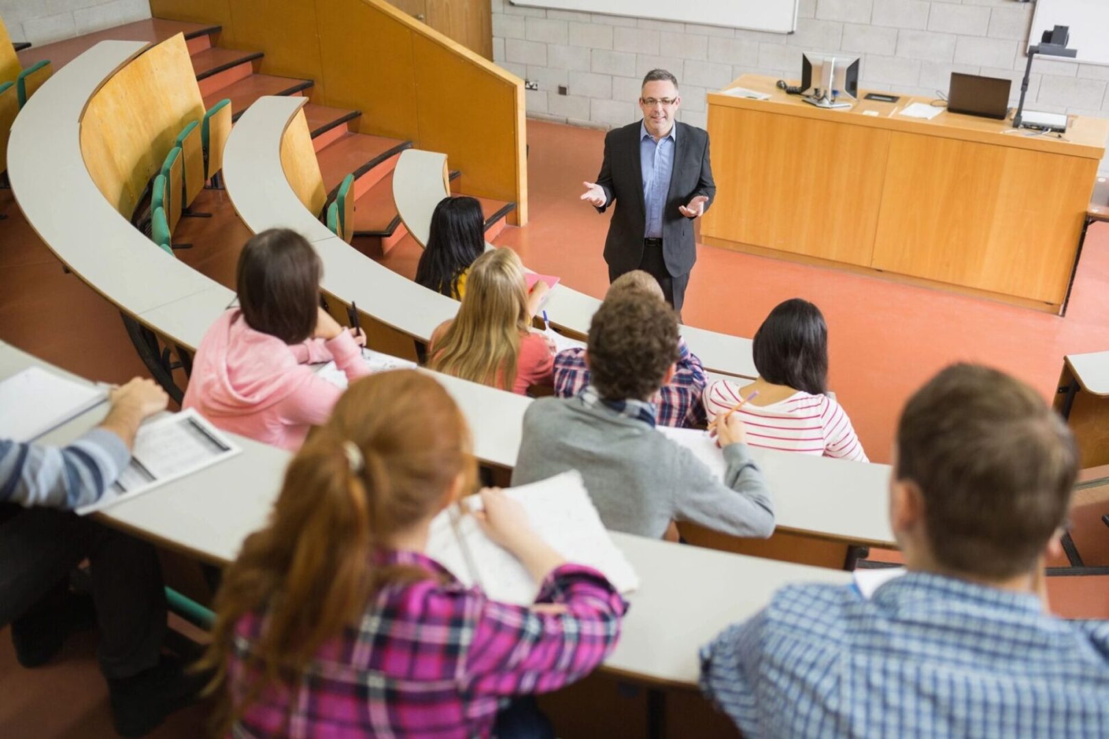 Professor lecturing to attentive university students in a classroom.